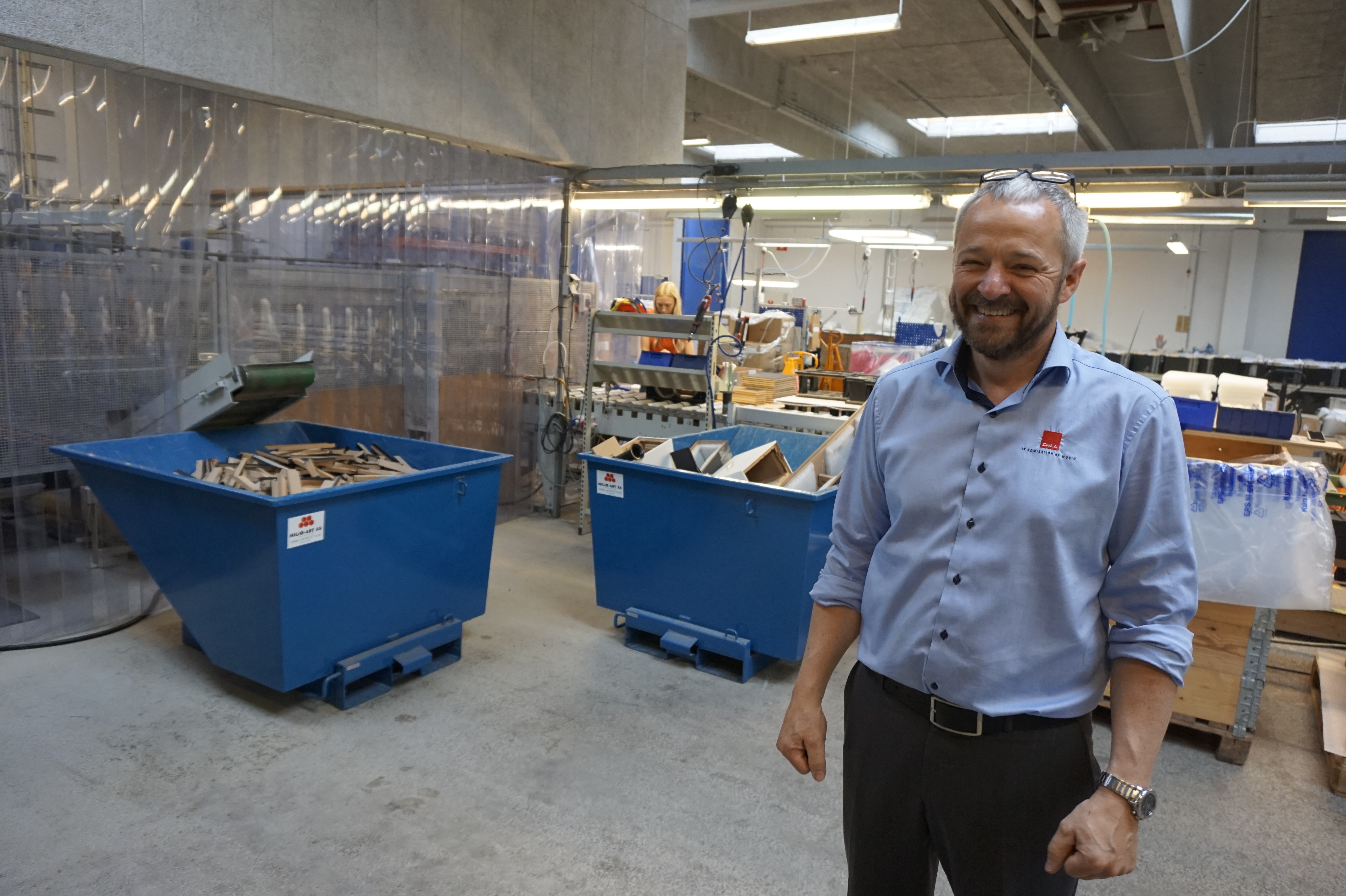 DALI-chefen Lars Worre visar runt på fabriken. I bakgrunden syns monteringslinjen med robotutskurna och -limmade kabinett. Foto: John Alex Hvidlykke