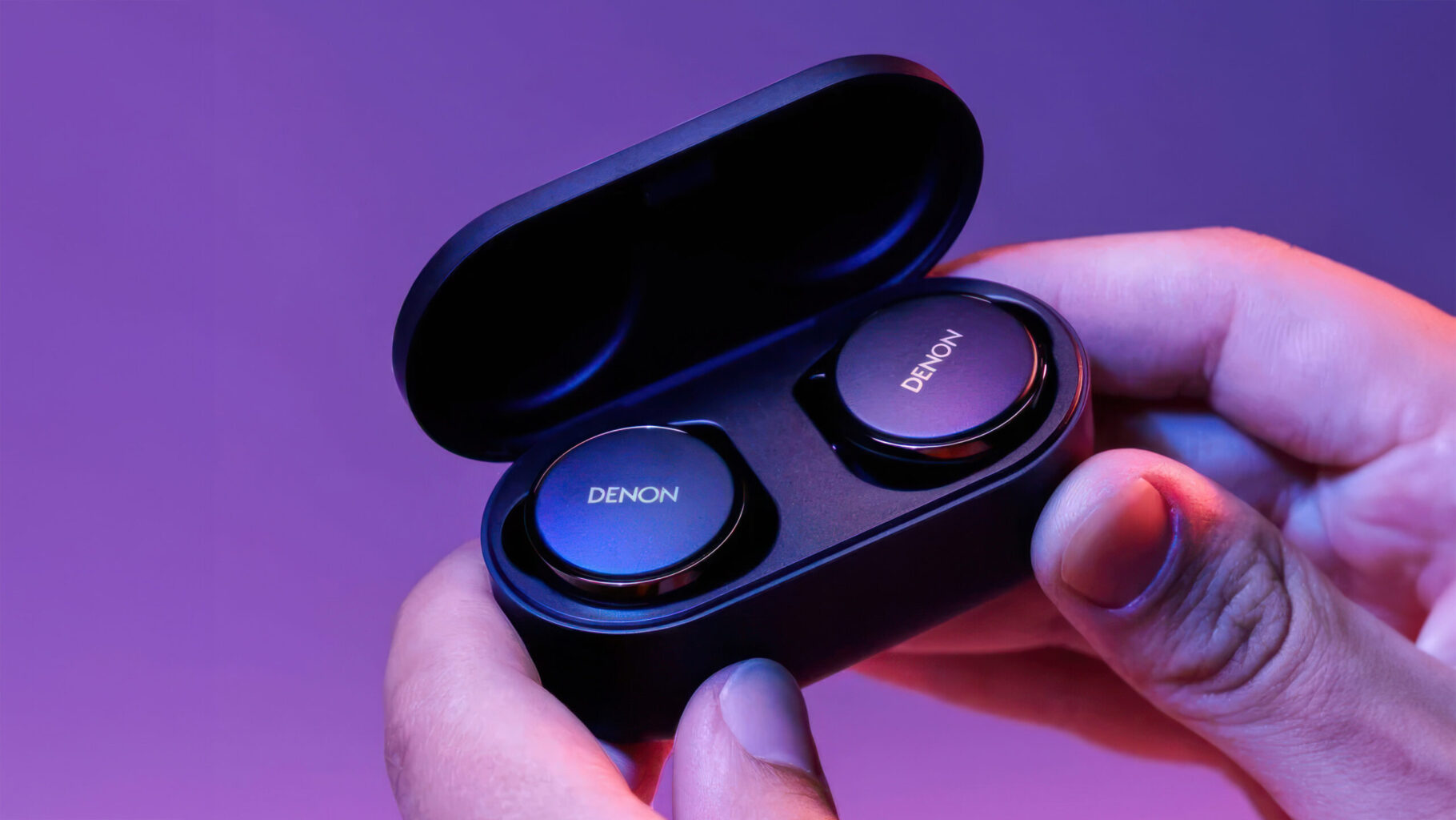 a person holding a black box with two round buttons Denon PerL Pro